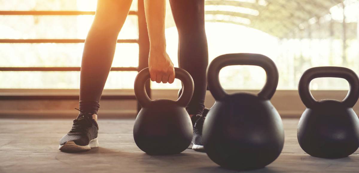 Fitness training with kettlebell in sport gym with sunlight effect